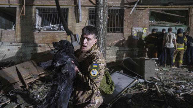A Ukrainian serviceman carries a dog out of a house damaged by a Russian airstrike on Kyiv. Picture; AP.