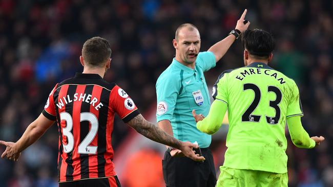 Referee Bobby Madley (C) speaks with Jack Wilshere (L) and Emre Can.
