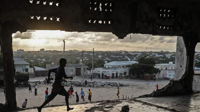 TOPSHOT - Somali children play football on a bulidling's upper floor as the sun sets in Mogadishu, Somalia, on June 7, 2018. / AFP PHOTO / Mohamed ABDIWAHAB