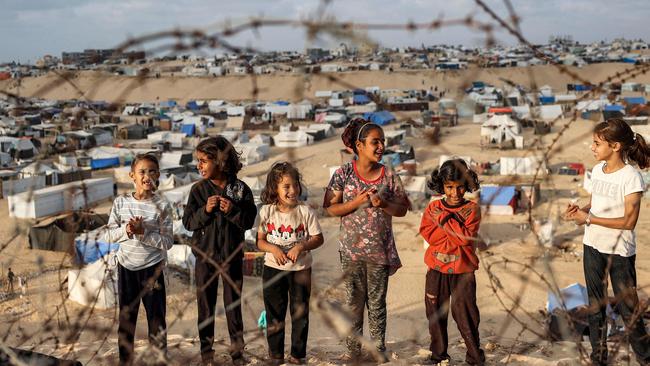 Children stand behind barbed-wire along a slope near a camp housing displaced Palestinians in Rafah. Picture: AFP