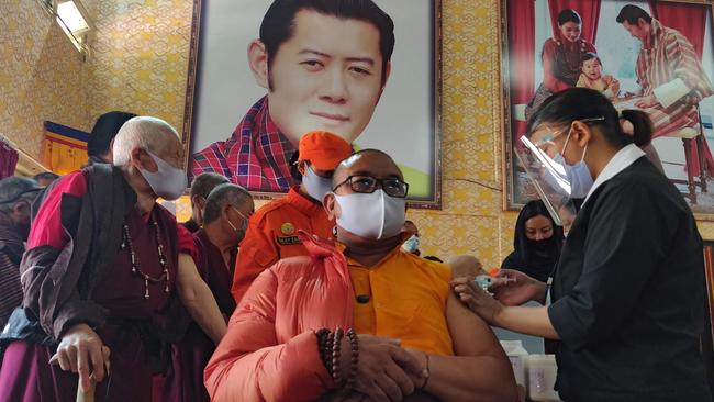 A health worker inoculates a Buddhist monk sitting in front of a portrait of Bhutan's King Jigme Khesar Namgyel Wangchuck during the first day of vaccination in Bhutan. Picture: AFP