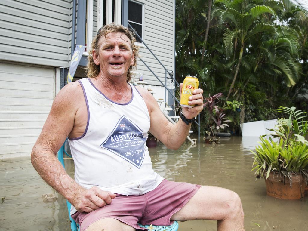 Greg Copnell, who stayed on at his Hermit Park home despite warnings, enjoys a beer in his front yard. Picture: Lachie Millard