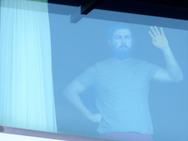 Jack O'Brien at the window of his Covid Hotel, Novotel Brisbane Airport. Photo Steve Pohlner