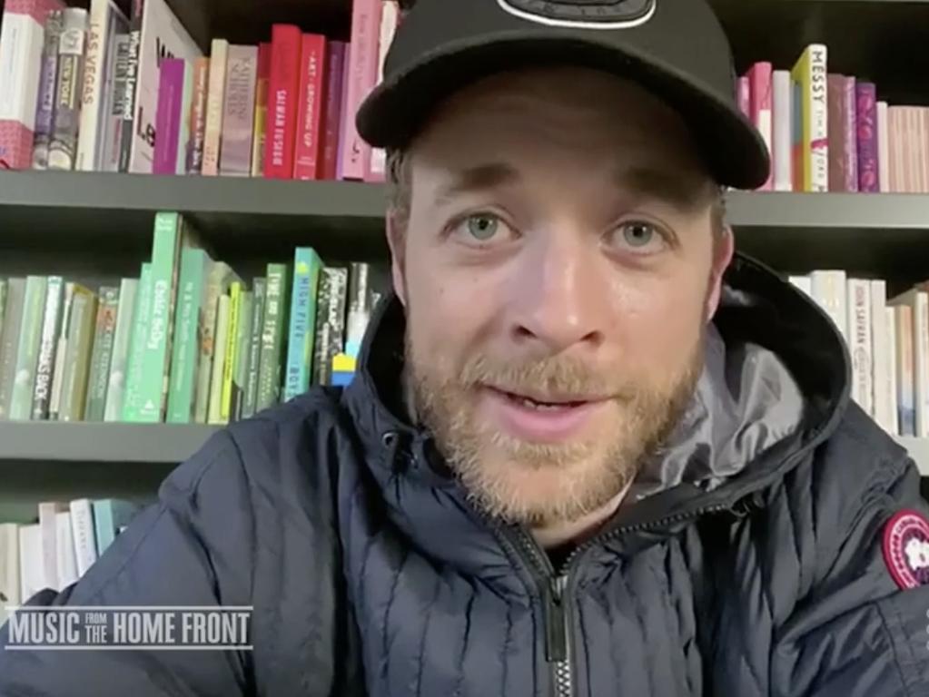 Hamish Blake in front of his colour-coded bookshelf.