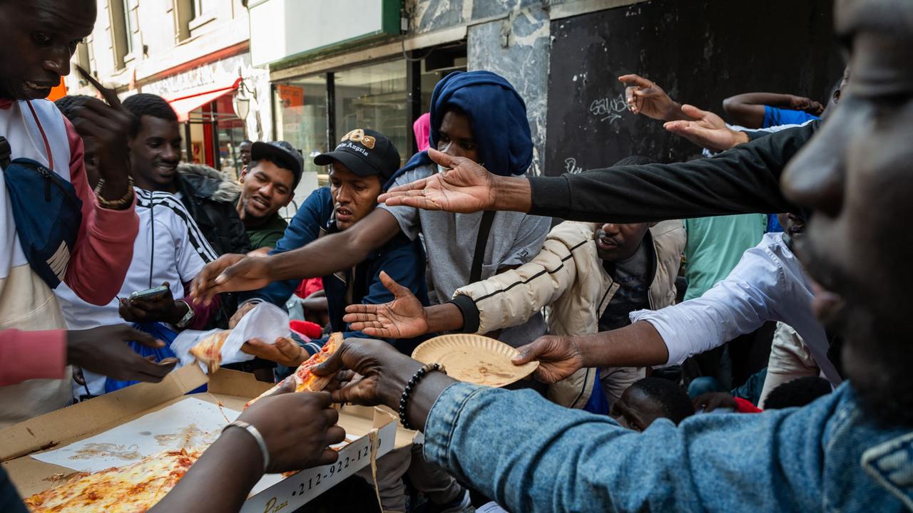 NEW YORK, NEW YORK - AUGUST 01: A police officer hands out pizza to dozens of recently arrived migrants to New York City as they camp outside of the Roosevelt Hotel, which has been made into a reception centre, where they try to secure temporary housing on August 01, 2023 in New York City. The migrants, many from Central America and Africa, have been sleeping on the streets or at other shelters as the city continues to struggle with the influx of migrants whose numbers have surged this spring and summer. Spencer Platt/Getty Images/AFP (Photo by SPENCER PLATT / GETTY IMAGES NORTH AMERICA / Getty Images via AFP)