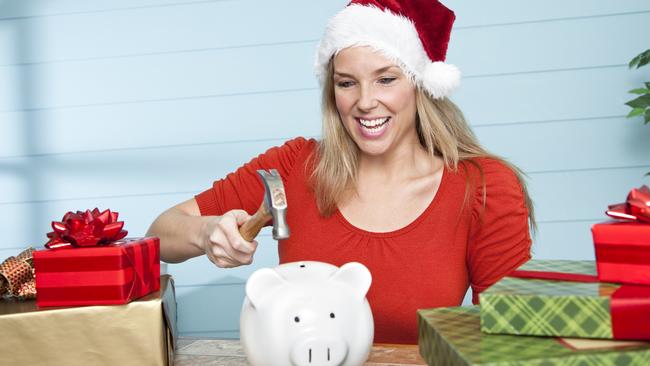 Happy woman wearing Santa hat about to break a piggy bank; Christmas spending debt money generic