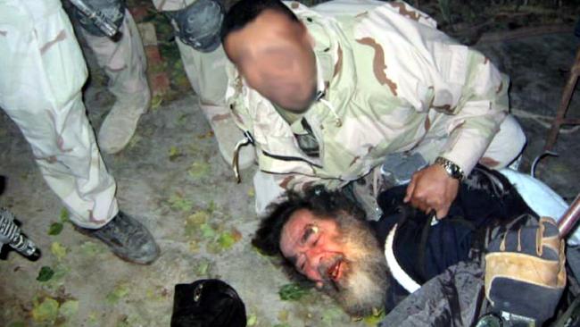 A US soldier drags Saddam Hussein from a hole he was hiding in.