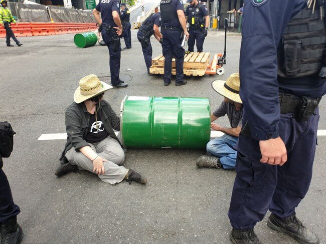 Protesters with their arms in barrels block George St in the city. Picture: Cloe Read