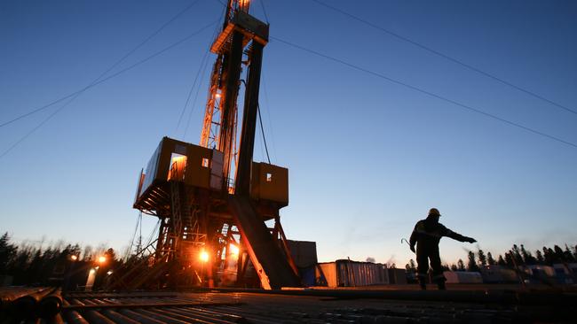 A worker passes an oil drilling rig in an oilfield in Russia. Photographer: Andrey Rudakov/Bloomberg