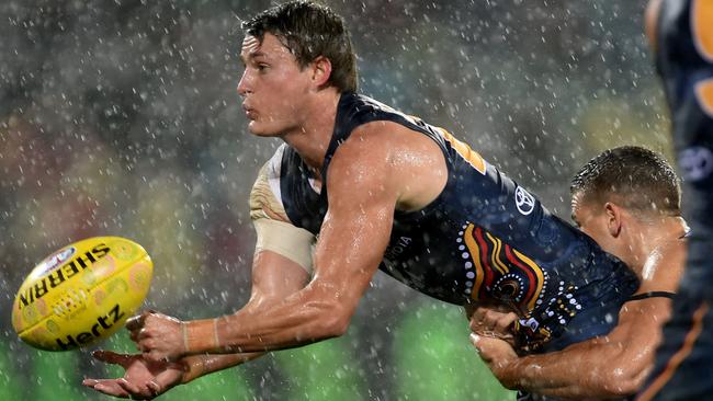 Matt Crouch gets his handball away fro the Crows as the rain tumbles down at Adelaide Oval. Picture: Sam Wundke