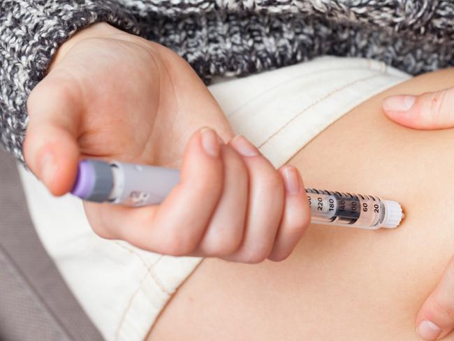 woman injecting herself in leg, shallow depth of field - epipen