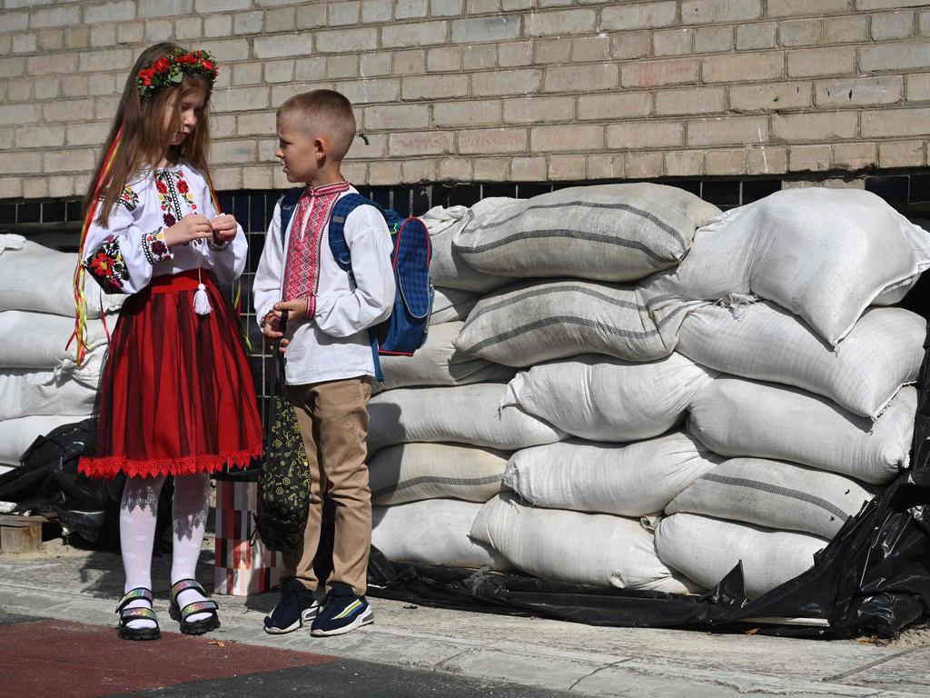 Ukrainian schoolchildren stand near protecting sand bags in the school yard after a First Bell ceremony, marking the beginning of the school year in the western Ukrainian city of Lviv on September 1, 2023. (Photo by YURIY DYACHYSHYN / AFP)