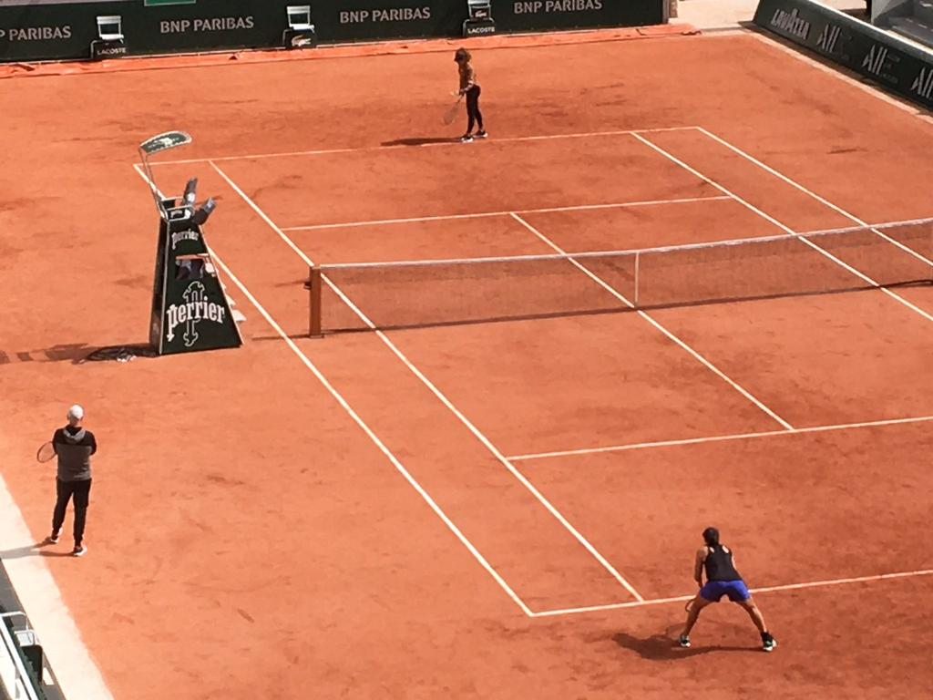 Ash Barty wait to receive Naomi Osaka's serve on the main court at Roland Garros.