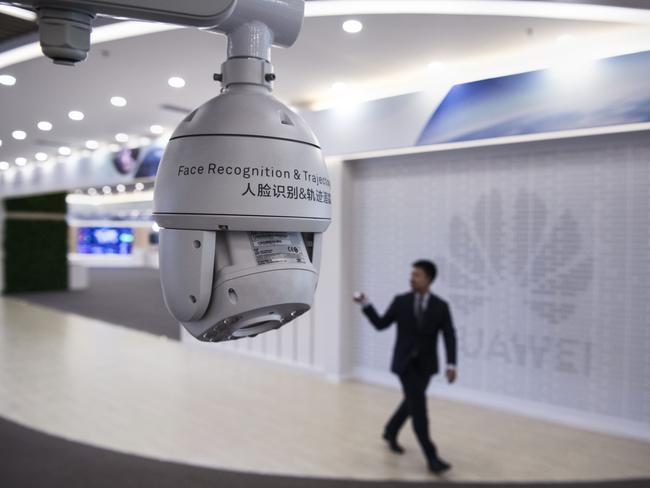 A Huawei reception employee walks by a display for facial recognition cameras at the company's Bantian campus. Picture: Kevin Frayer