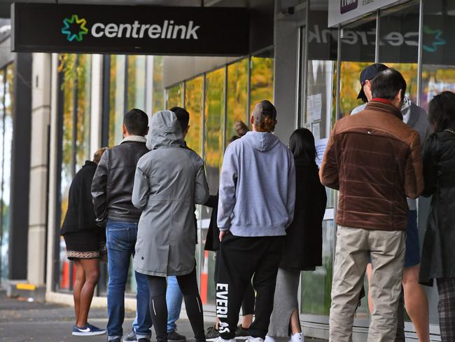 People queue up outside a Centrelink office in Melbourne on April 20, 2020, which delivers a range of government payments and services for retirees, the unemployed, families, carers and parents amongst others. - A report from the Grattan Institute predicts between 14 and 26 per cent of Australian workers could be out of work as a direct result of the coronavirus shutdown, and the crisis will have an enduring impact on jobs and the economy for years to come. (Photo by William WEST / AFP)