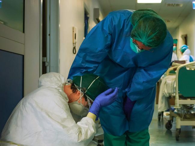 A nurse wearing protective mask and gear comforts another as they change shifts on March 13, 2020 at the Cremona hospital, southeast of Milan, Lombardy, during the country's lockdown aimed at stopping the spread of the COVID-19 (new coronavirus) pandemic. - After weeks of struggle, they're being hailed as heroes. But the Italian healthcare workers are exhausted from their war against the new coronavirus. (Photo by Paolo MIRANDA / AFP) / RESTRICTED TO EDITORIAL USE - MANDATORY CREDIT "AFP PHOTO / PAOLO MIRANDA" - NO MARKETING - NO ADVERTISING CAMPAIGNS - DISTRIBUTED AS A SERVICE TO CLIENTS