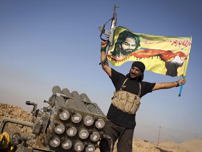 An Iraqi militia fighter from Shiite cleric Moqtada al-Sadr's Saraya al-Salam (Peace Brigade), waves a flag next to a rocket launcher during heavy clashes with Islamic State. AFP PHOTO/ JM Lopez