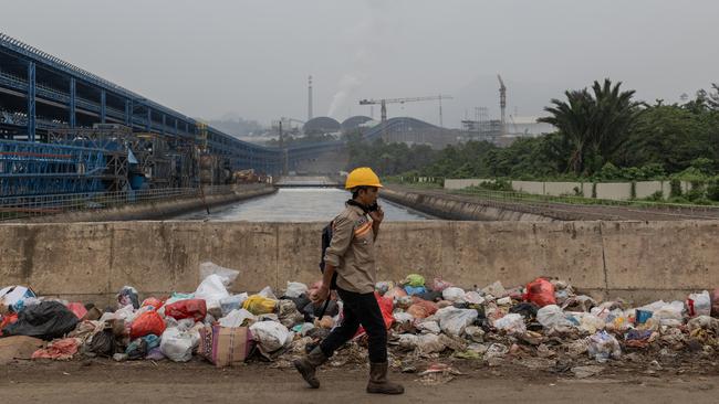 A worker passes by the belching chimneys of Indonesia Morowali Industrial Park (IMIP), a nickel processing complex in Morowali, Central Sulawesi, Indonesia. Picture: Garry Lotulung