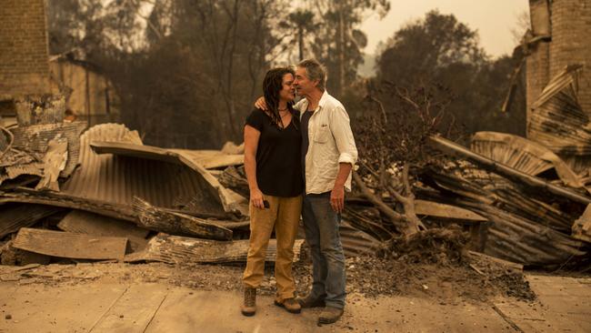 Cobargo business owner Sally Anne Wilson stands in front of her destroyed shop with her partner Christopher Lee in the NSW town. Picture: AAP / Sean Davey