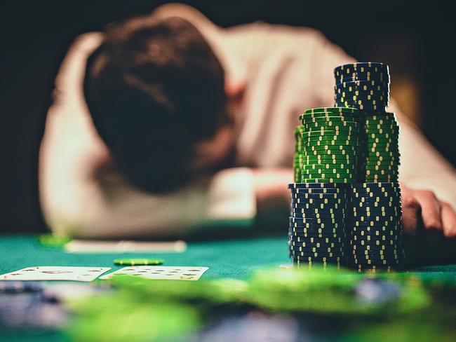 One young man playing poker game late by night and losing in game.