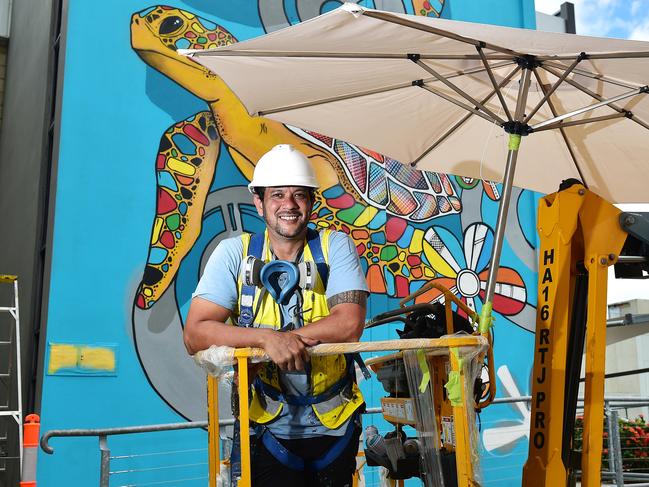 Darwin artist Hafleg puts the finishing touches to his street art mural which is on the side of the city police station. Picture: Shae Beplate.