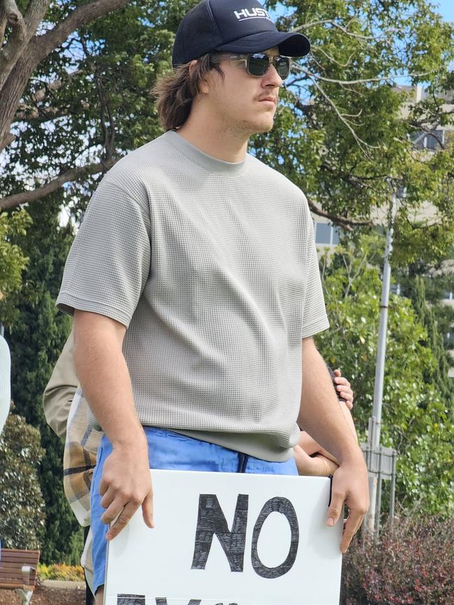 Hayden Brook holds a sign as more than 100 people march in the No More Violence Rally in Toowoomba's Queens Park, organised by volunteer group What Were You Wearing to advocate for more funding to stop domestic and family violence.