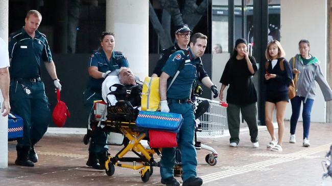 Paramedics and police escort a man injured in a fight at Australia Fair. Picture: Nigel Hallett