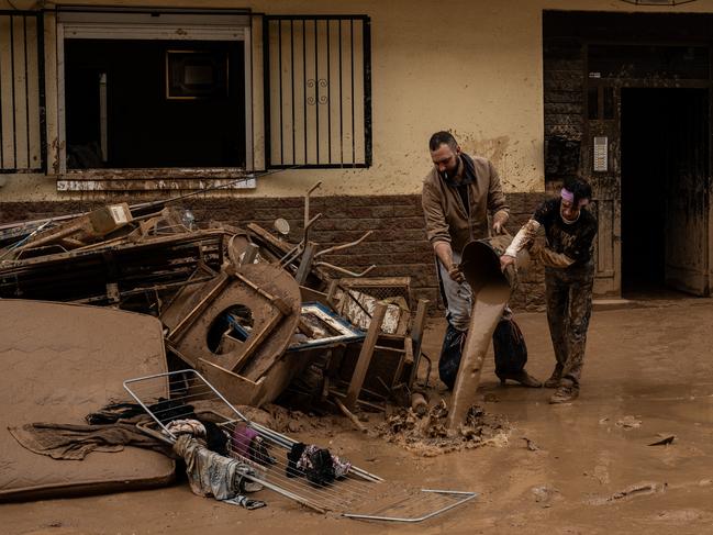 People clear mud and possessions from their homes. Picture: Getty