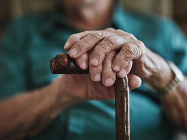 Cropped shot of an unrecognizable man leaning on his walking stick