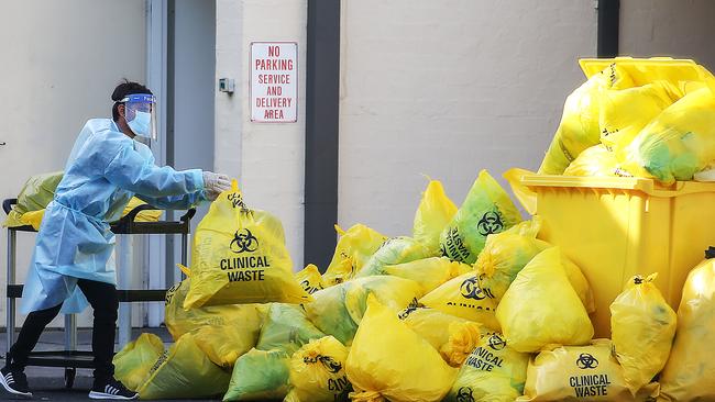 A worker dumps another bag of clinical waste outside St Basil’s Home for the Aged in Melbourne’s north on Friday. Picture: Ian Currie