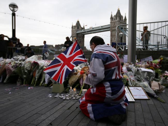 A man holds a Union Jack flag as he kneels near flowers at Potters Fields Park in London during a vigil to commemorate the victims of the terror attack on London Bridge and at Borough Market that killed seven people. Picture: AFP/Daniel Leal-Olivas