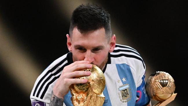 Argentina's captain and forward #10 Lionel Messi kisses the FIFA World Cup Trophy.