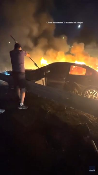 Dramatic footage shows good samaritans drag men from burning car.