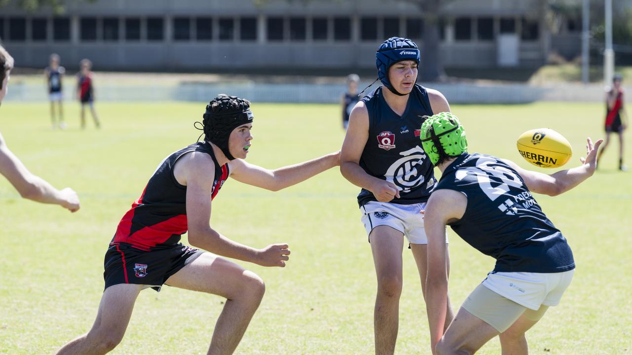 Flynn Goodall (centre) handballs to Cameron Dennis for Coolaroo under pressure from Peter Dunn of South Toowoomba Bombers in U14 AFL Darling Downs grand final at Rockville Park, Saturday, September 2, 2023. Picture: Kevin Farmer