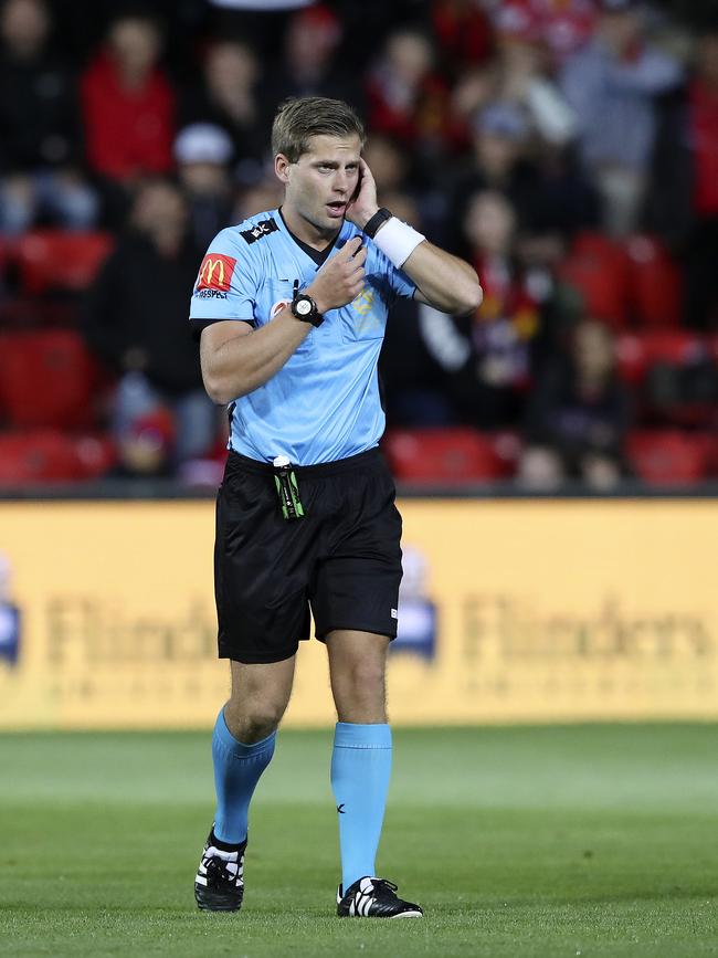 Referee Alex King listens to instructions from the VAR.