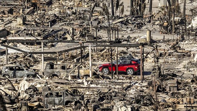 A car drives past homes and vehicles destroyed by the Palisades Fire. Picture: AP