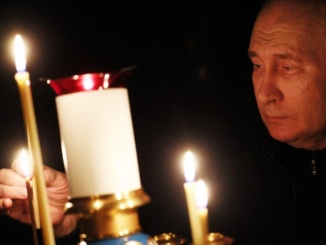 Vladimir Putin lights a candle during his visit to a church of the Novo-Ogaryovo state residence outside Moscow. Picture: AFP.