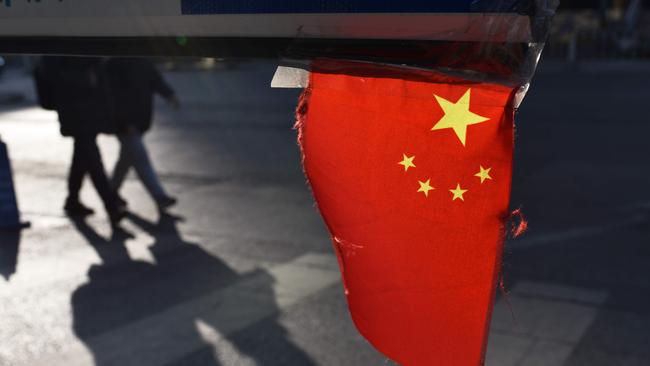 A Chinese national flag hangs from a barrier in a car park in Beijing on January 18, 2018. China's economy grew a forecast-beating 6.9 percent in 2017, picking up steam for the first time since 2010 despite its battles against a massive debt and polluting factories, official data showed on January 18. / AFP PHOTO / Greg Baker