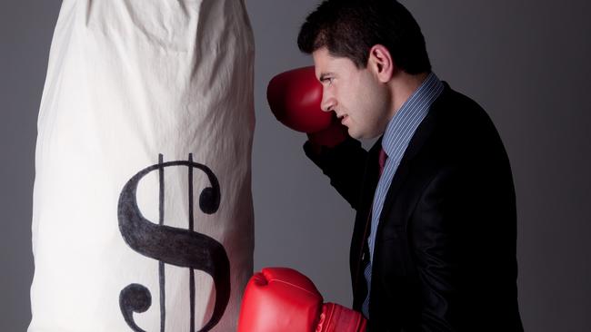 Businessman punching money bag with boxing gloves; dollar sign money generic