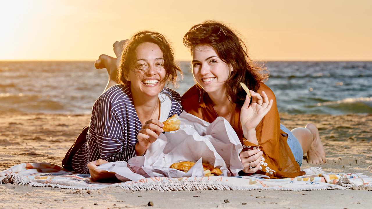 Beverly Hilton and Grace Walker eat fish and chips at Glenelg Beach. Picture: Matt Loxton
