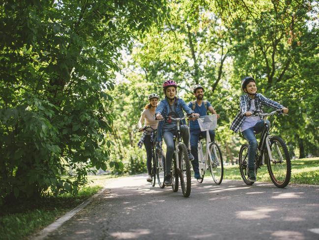 Family riding bicycle in the public park together. Cycling and enjoying the sunny day