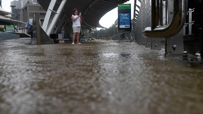 An observer weathers the downpour to document it on her phone. Picture: Bianca De Marchi