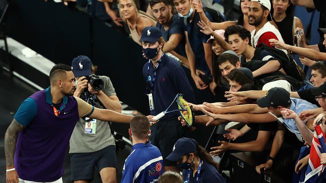 Nick Kyrgios hands over his broken racquet as a souvenir to the crowd.