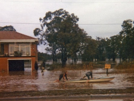 Barry du Bois and his brother Michael play on a small boat across the flooded Newbridge Rd near their home.