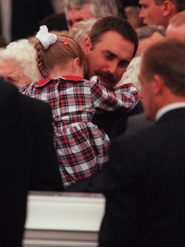 Widower Mark Thurgood-Dove comforts his daughter as his wife's coffin is taken away.