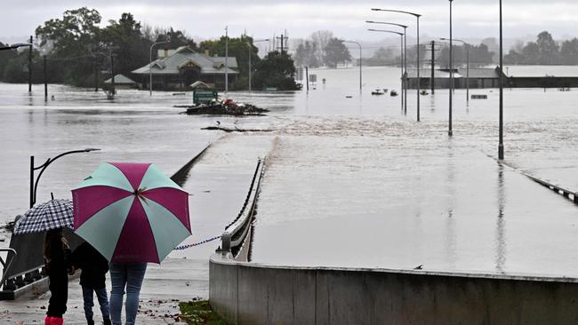 Residents look out toward flooded buildings next to the old Windsor Bridge along the overflowing Hawkesbury River on Monday July 4. Picture: Saeed Khan / AFP