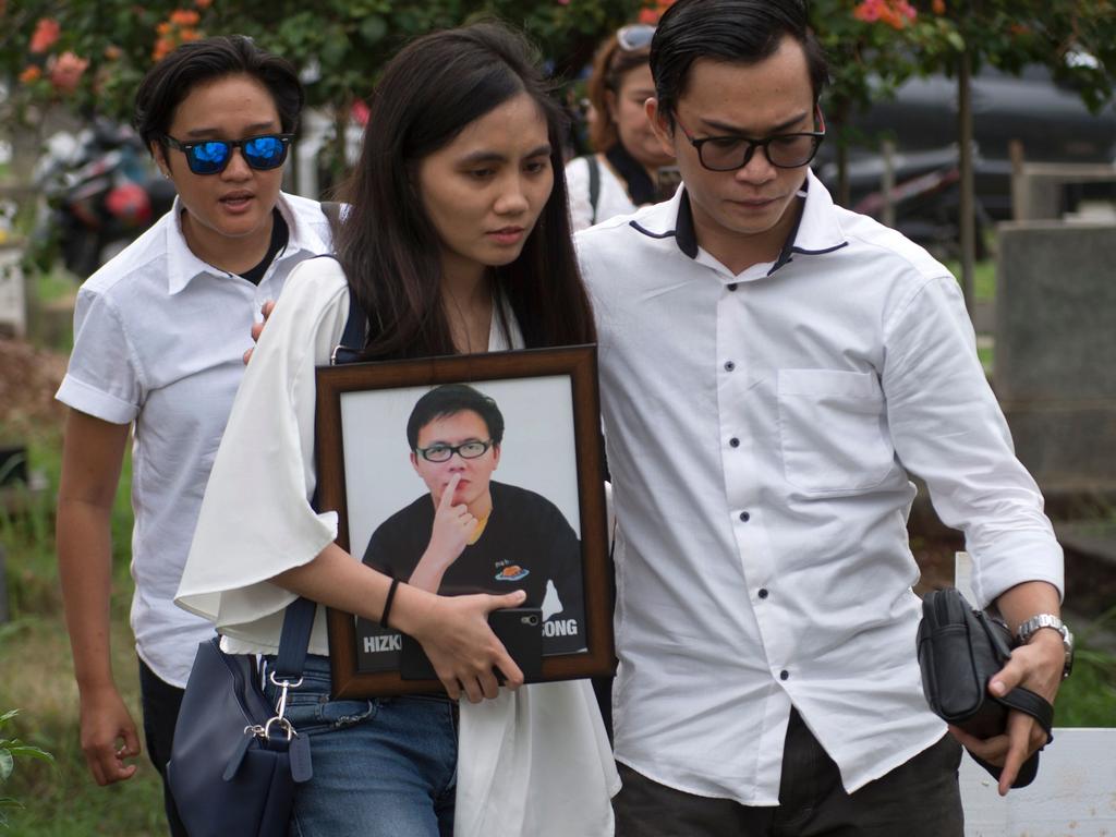 Kezia, a sister of Hizkia Jorry Saroinsong, a passenger on the ill-fated Lion Air flight JT 610, carries her brother's portrait during his funeral in Jakarta. Picture: AFP