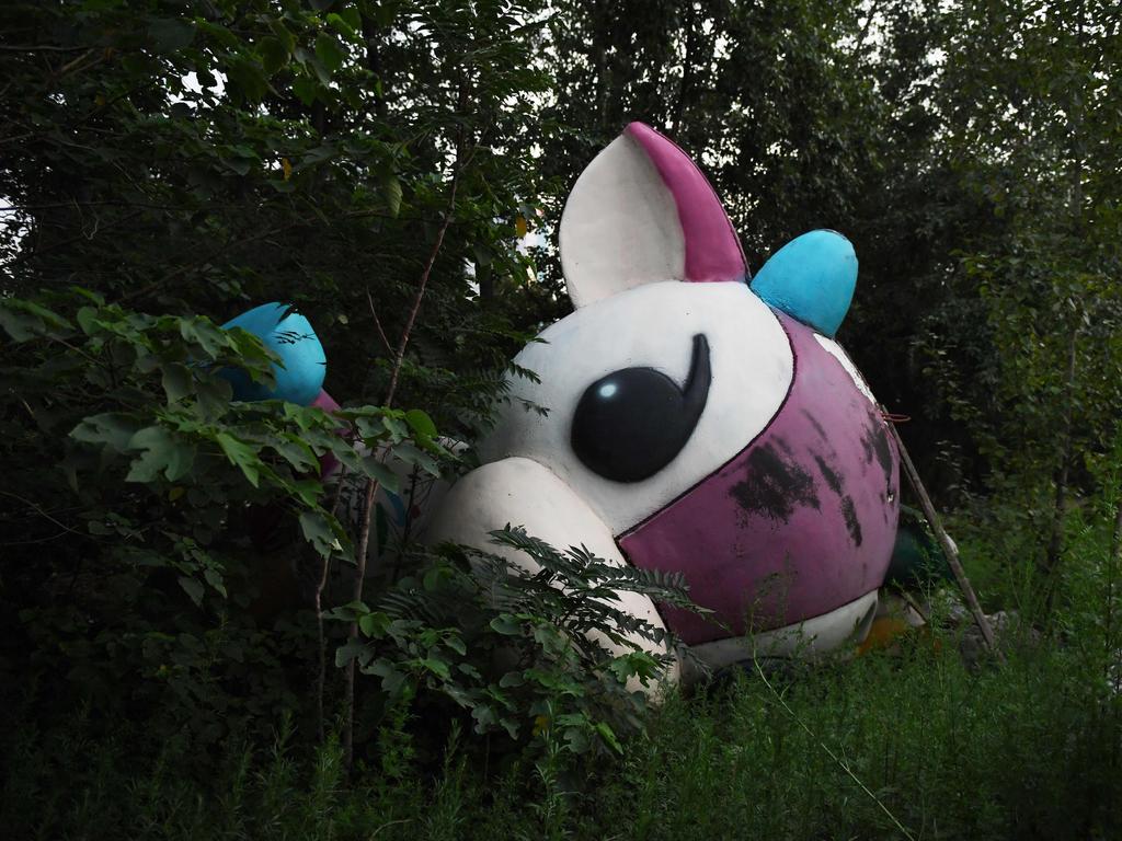 Fu Niu Lele, the mascot for the 2008 Beijing Paralympic Games, lying among trees behind an abandoned, never-completed mall in Beijing