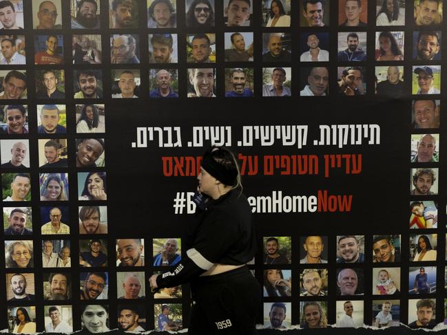 TEL AVIV, ISRAEL - DECEMBER 28: A woman walks by a wall covered with photos of hostages held by Hamas in the Gaza Strip in a train station on December 28, 2024 in Tel Aviv, Israel. Former hostages, family members of hostages, and thousands of their supporters are rallying for a deal to be made with Hamas to return the 100 people who remain captive in Gaza. The Israeli government and Hamas have blamed each other for stalled negotiations, after talks appeared to build momentum in recent weeks. (Photo by Amir Levy/Getty Images)