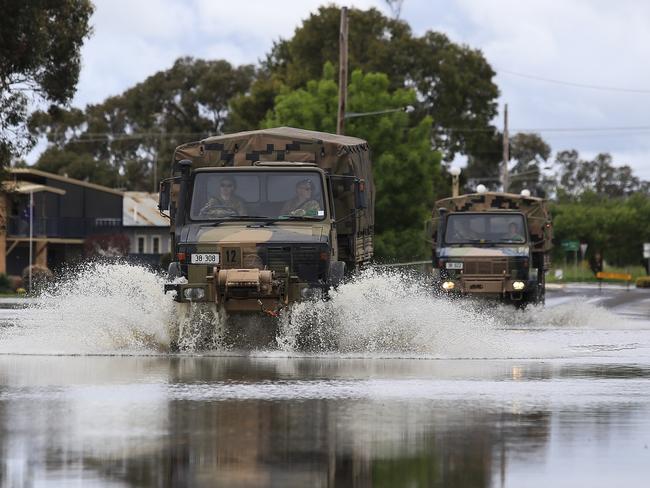 Army trucks drive down Camp St during a route check as Lake Forbes floods over the road. Picture: Dylan Robinson